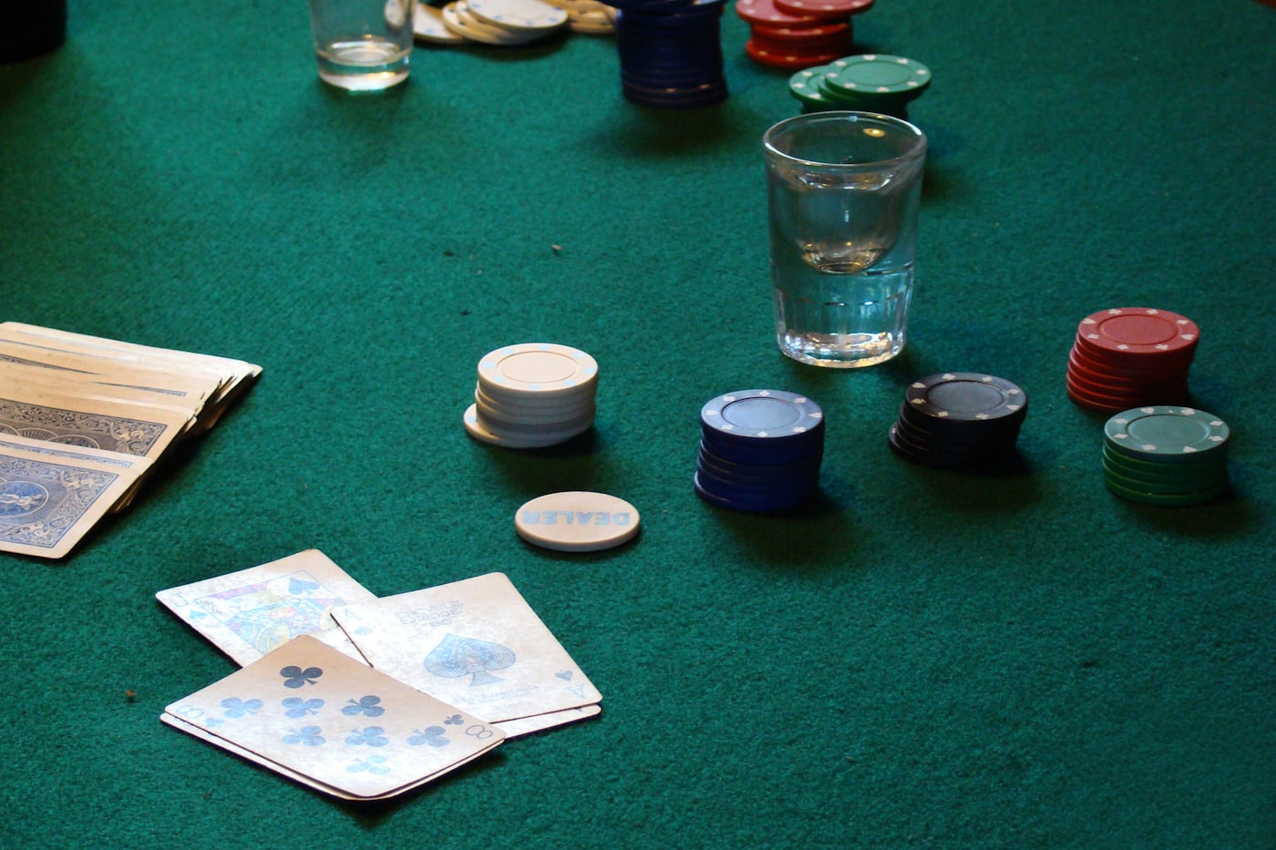 Poker chips and playing cards on a green felt table under warm light