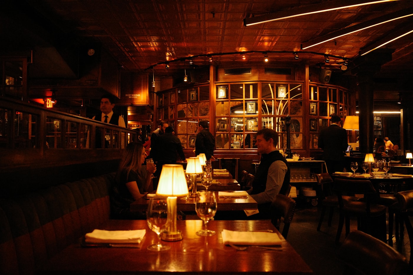 Dimly lit fine dining restaurant with candlelit tables and moody ambient lighting